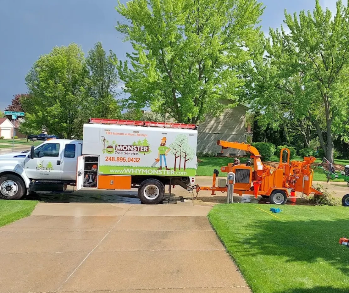 Monster Tree Service truck and wood chipper parked at a home